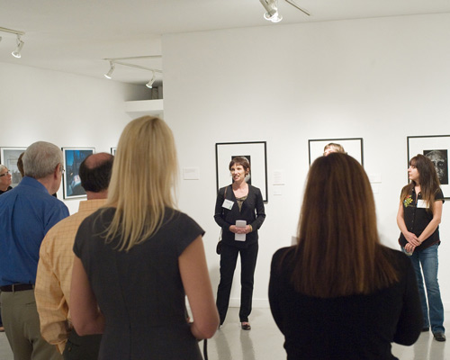 A woman speaking to visitors at a photography exhibition